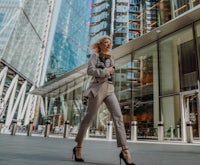 a woman in a suit walking down a street in london