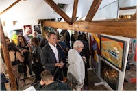 a group of people looking at paintings in an art gallery