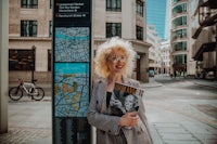 a woman holding a magazine in front of a street sign in london